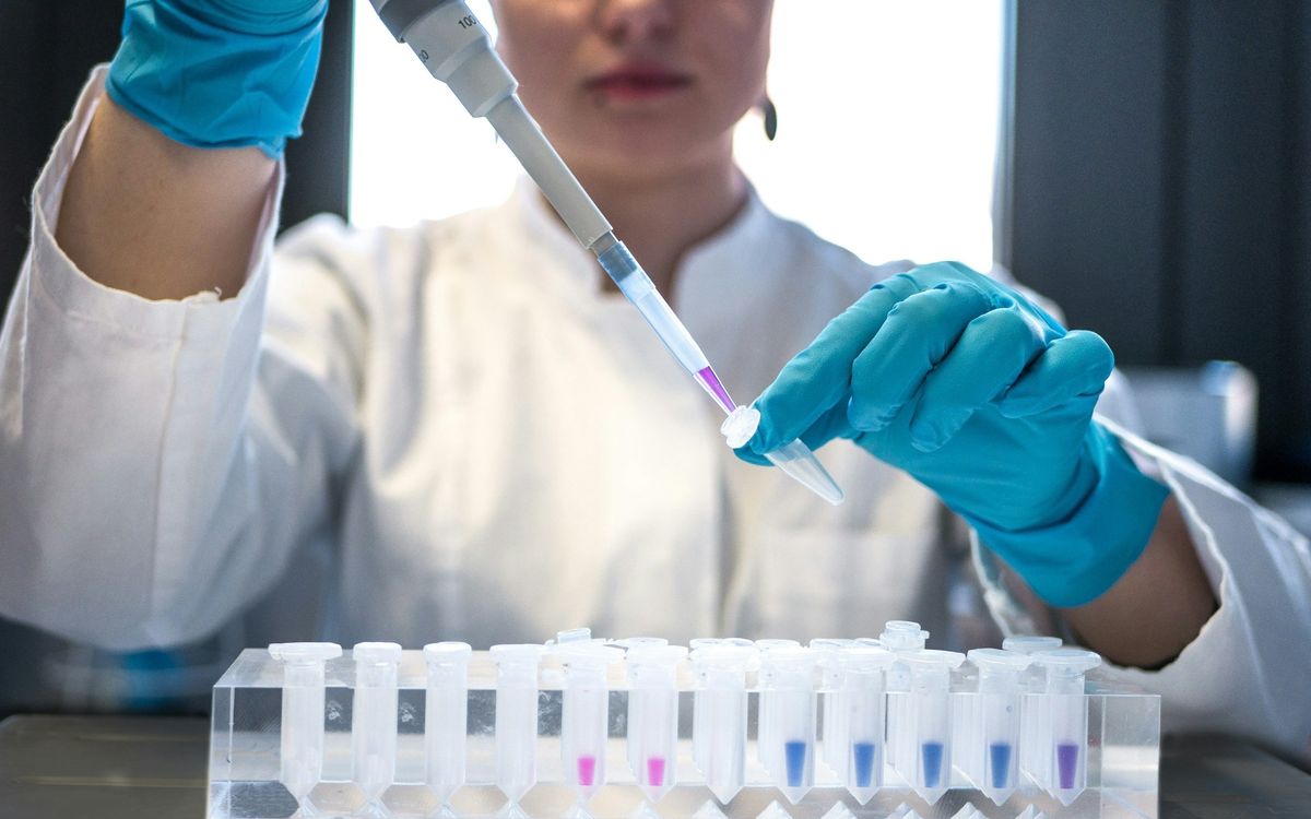 Científica con guantes azules trabajando con muestras de laboratorio