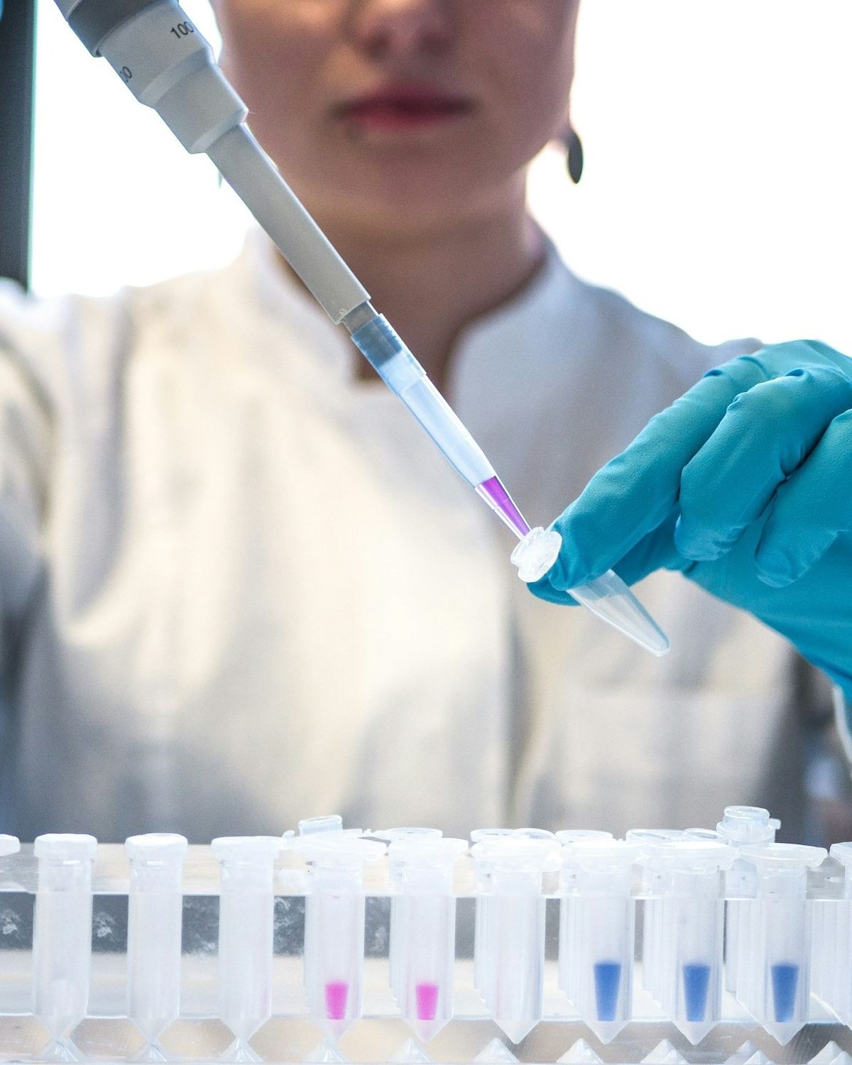 Científica con guantes azules trabajando con muestras de laboratorio